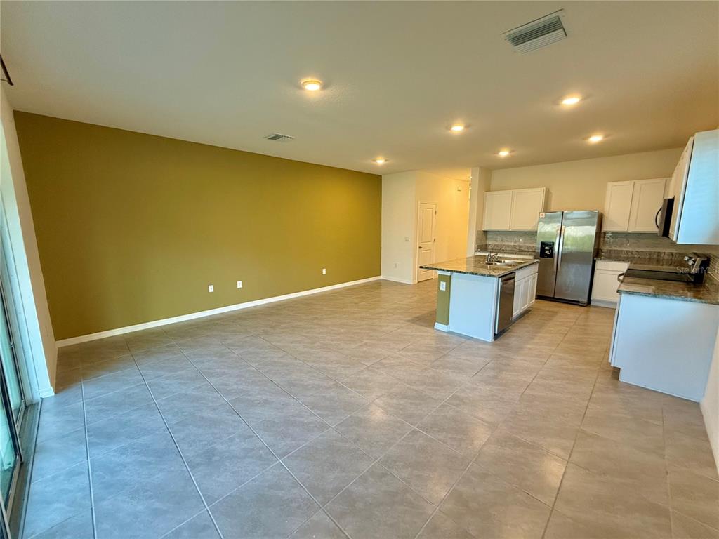 An open-concept kitchen and living area features tile flooring, a center island, and stainless appliances — 34309 SORREL MINT DRIVE, WESLEY CHAPEL, FL