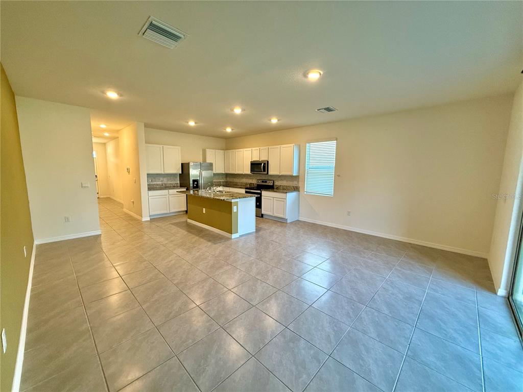 An open-concept kitchen features white cabinetry, a central island, and tile flooring — 34309 SORREL MINT DRIVE, WESLEY CHAPEL, FL