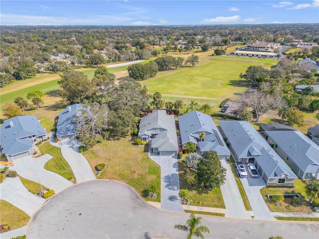 An aerial view shows several houses with gray roofs situated along a cul-de-sac near a golf course — 1098 RED MAPLE WAY, NEW SMYRNA BEACH, FL