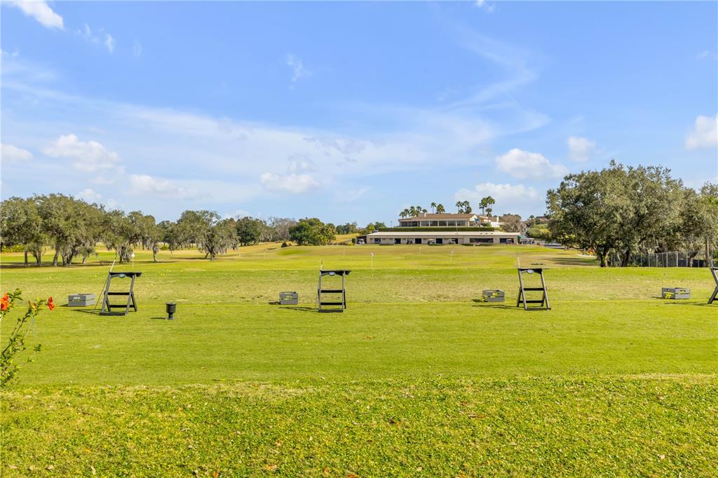 A view of a golf driving range with several hitting stations and a clubhouse building — 1098 RED MAPLE WAY, NEW SMYRNA BEACH, FL