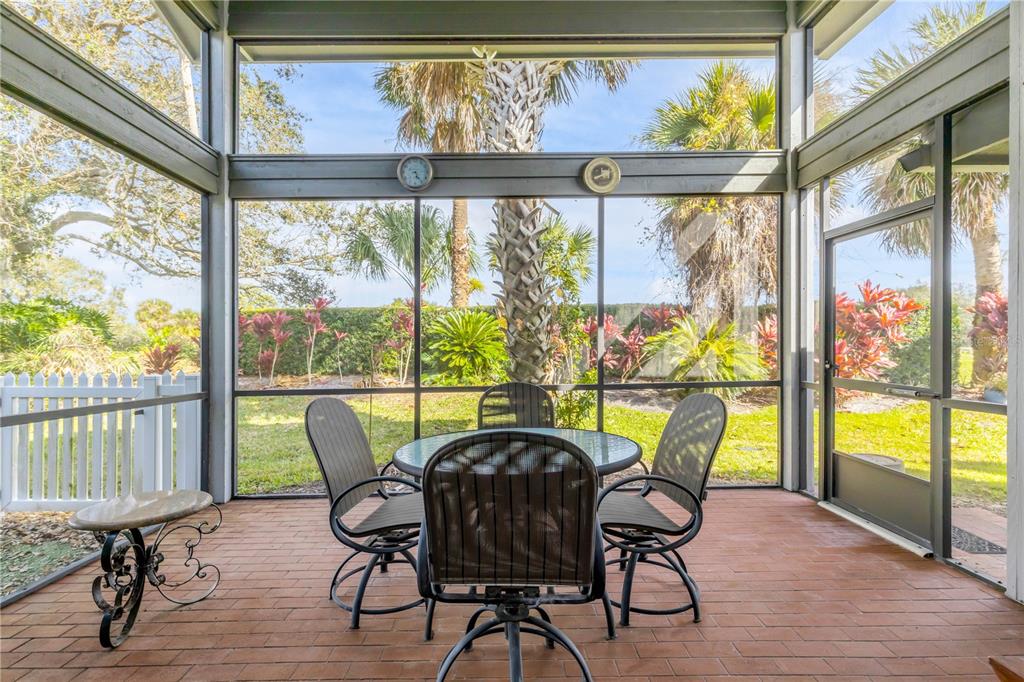 A screened-in porch features a brick floor, a dining set, and views of palm trees — 1098 RED MAPLE WAY, NEW SMYRNA BEACH, FL