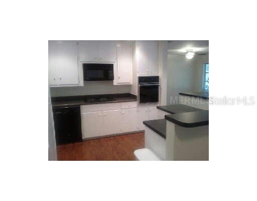 A kitchen features white cabinets, black countertops, a built-in oven, and a microwave — 2711 LYNNHURST STREET, SARASOTA, FL