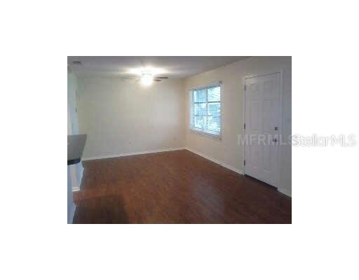An empty room features wood-look flooring, a ceiling fan, a window, and a white door — 2711 LYNNHURST STREET, SARASOTA, FL