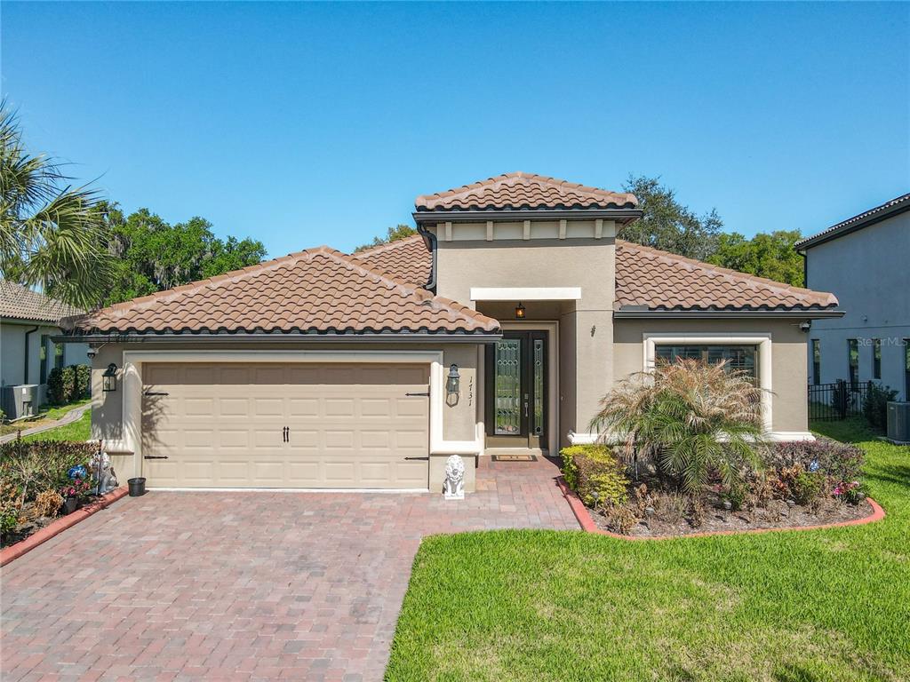 A single-story house with a tan stucco exterior, a tile roof, and a paved driveway — 1731 GOBLET COVE STREET, KISSIMMEE, FL
