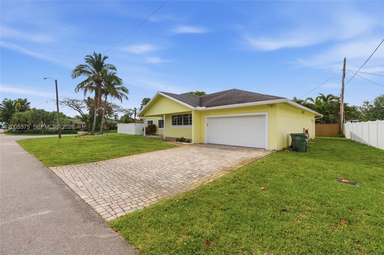 A yellow single-story house features a paved driveway, a two-car garage, and a grassy lawn — 4361 NE 13th Ter, Oakland Park FL 33334, OAKLAND PARK, FL