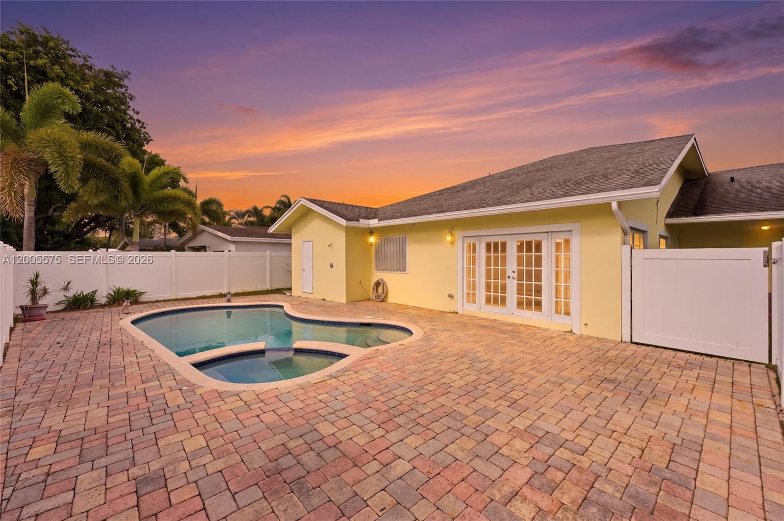 A backyard features a swimming pool, a brick paver patio, and a yellow house — 4361 NE 13th Ter, Oakland Park FL 33334, OAKLAND PARK, FL