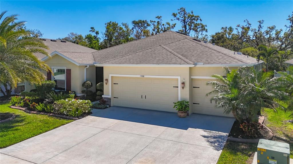 A single-story house with a beige exterior, a two-car garage, and a concrete driveway — 15208 LAS OLAS PLACE, BRADENTON, FL