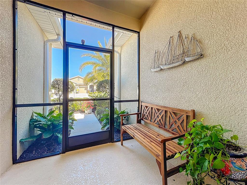 A screened-in entryway features a wooden bench, wall decor, and a view of the outdoors — 15208 LAS OLAS PLACE, BRADENTON, FL