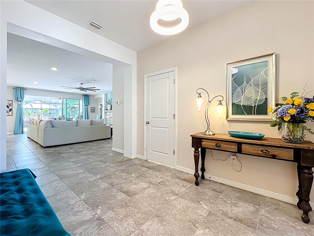 A tiled entryway features a wooden console table, a modern light fixture, and a white door — 15208 LAS OLAS PLACE, BRADENTON, FL