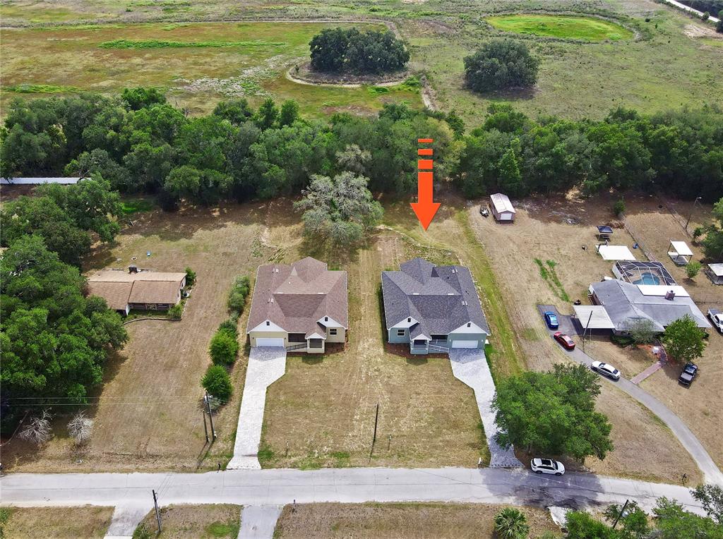 An aerial view shows two suburban houses with driveways situated on a large grassy lot — 12484 GREEN OAK LANE, DADE CITY, FL