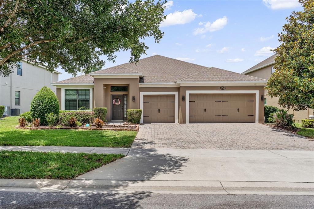 A single-story house with a tan exterior, a three-car garage, and a paved driveway — 5716 RUE GALILEE LANE, SANFORD, FL