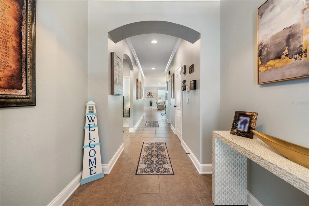 A tiled hallway features arched entryways, a welcome sign, and a console table — 5716 RUE GALILEE LANE, SANFORD, FL