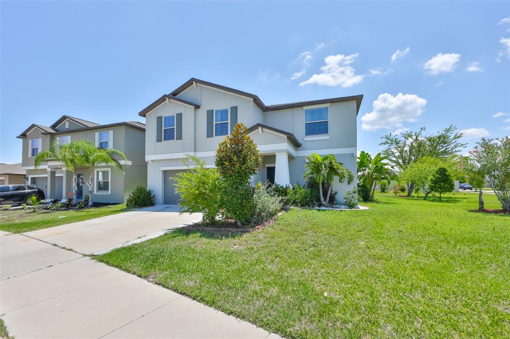 A two-story suburban house with a concrete driveway, green lawn, and palm trees — 11503 SAGE CANYON DRIVE, RIVERVIEW, FL