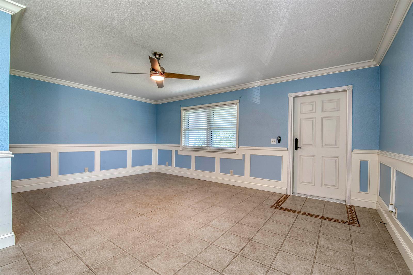 An empty room features light blue walls, white wainscoting, tile flooring, and a ceiling fan — 960 Flanders T, Delray Beach FL 33484, DELRAY BEACH, FL