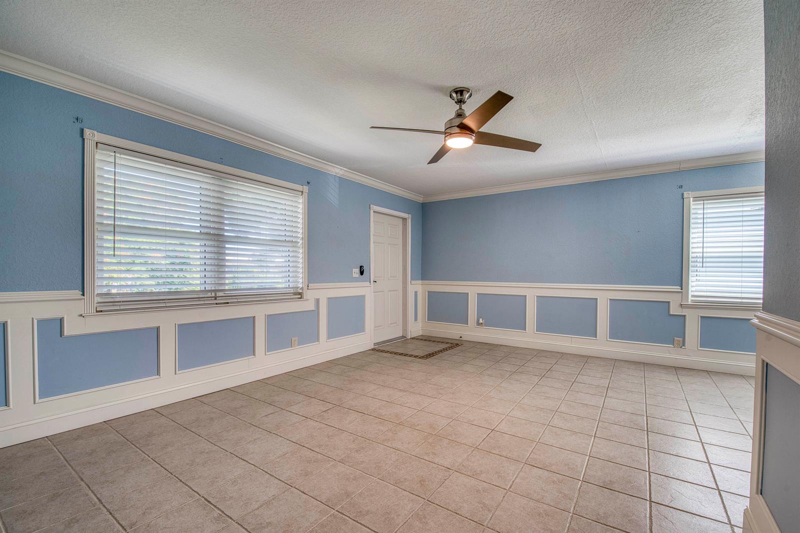 A room with light blue walls, white wainscoting, tile flooring, and a ceiling fan — 960 Flanders T, Delray Beach FL 33484, DELRAY BEACH, FL