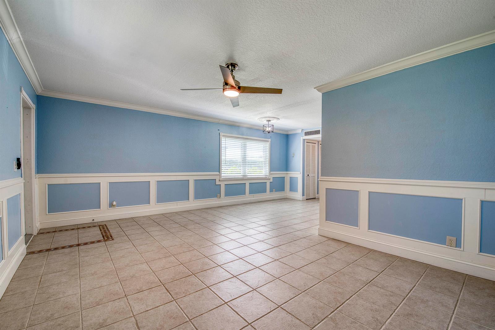 An empty room with blue walls, white wainscoting, tile flooring, and a ceiling fan — 960 Flanders T, Delray Beach FL 33484, DELRAY BEACH, FL