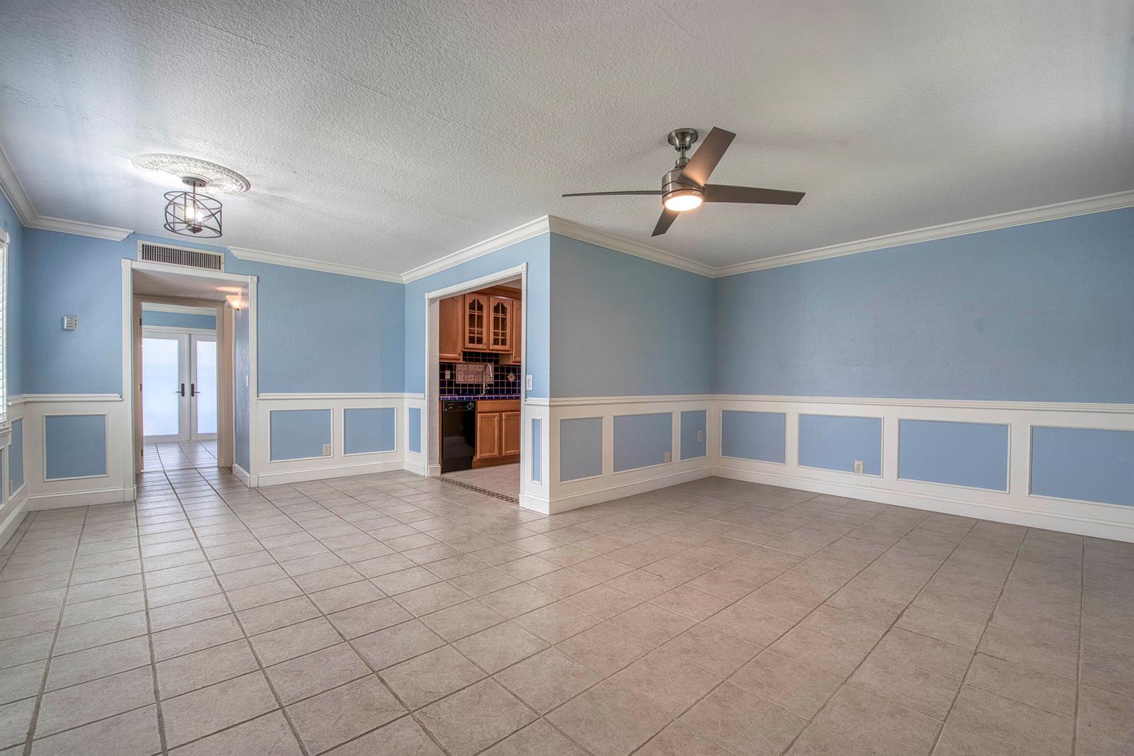 An empty room with light blue walls, white wainscoting, tile flooring, and a ceiling fan — 960 Flanders T, Delray Beach FL 33484, DELRAY BEACH, FL