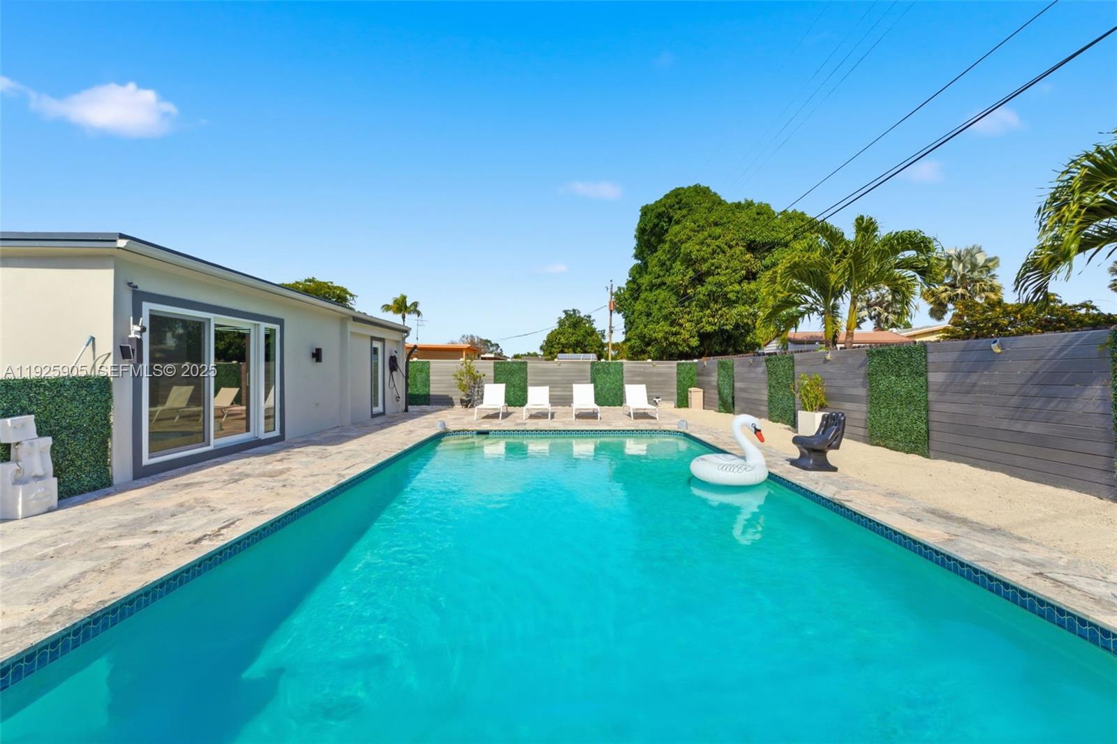 A backyard features a rectangular swimming pool with a white swan float and lounge chairs — 251 N 71st Ave # 251, Hollywood FL 33024, HOLLYWOOD, FL