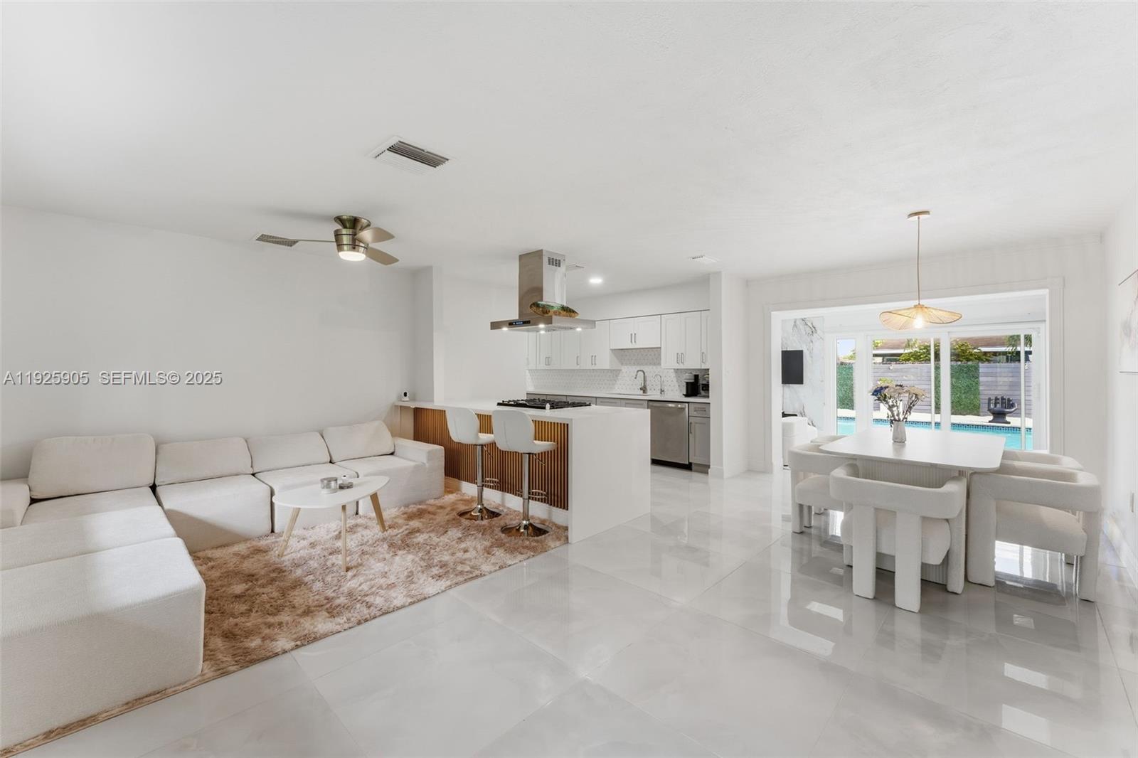 An open-concept living room, kitchen, and dining area featuring white furniture and tile flooring — 251 N 71st Ave # 251, Hollywood FL 33024, HOLLYWOOD, FL