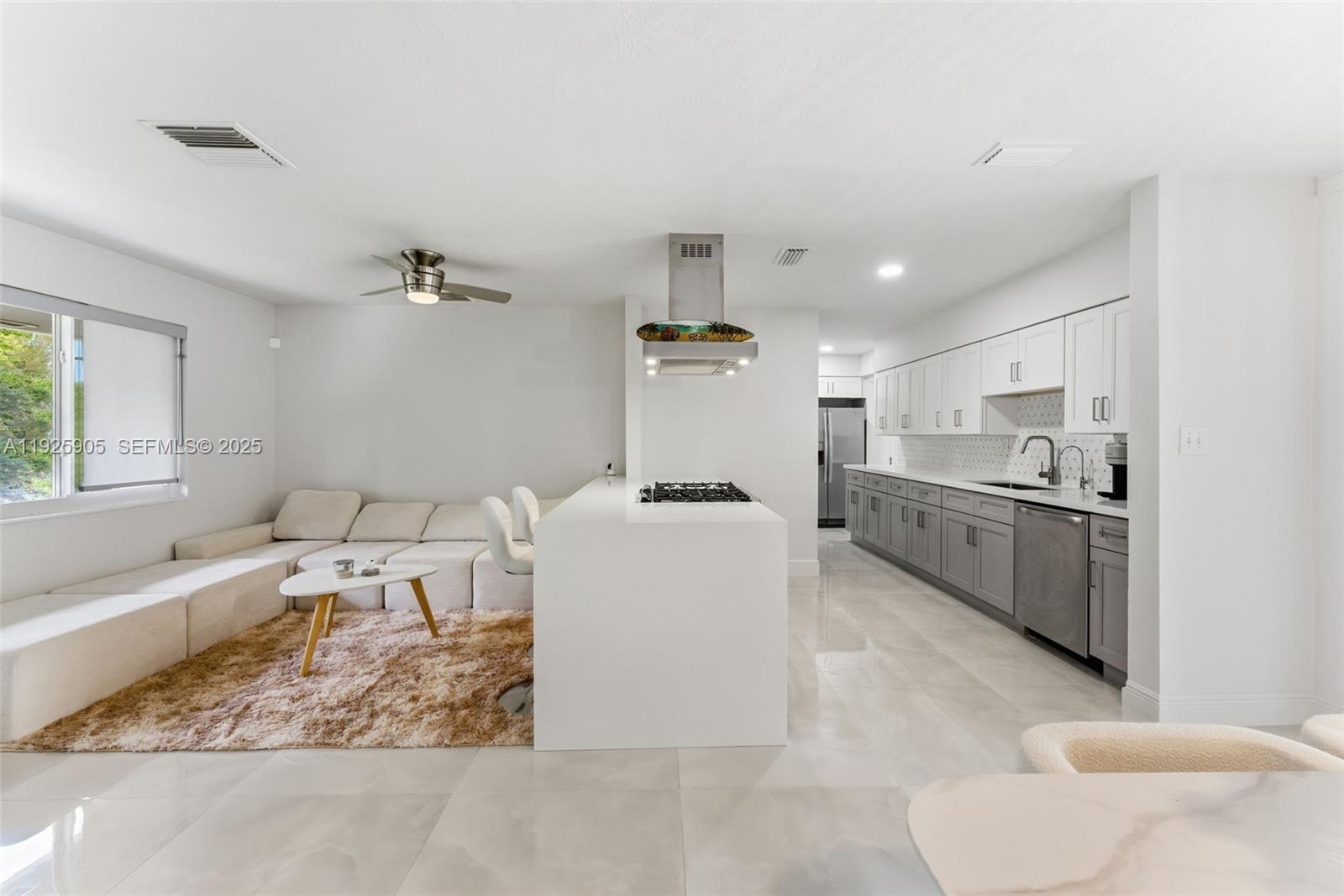 A modern open-concept kitchen features a white island, gray cabinetry, and an adjacent living area — 251 N 71st Ave # 251, Hollywood FL 33024, HOLLYWOOD, FL