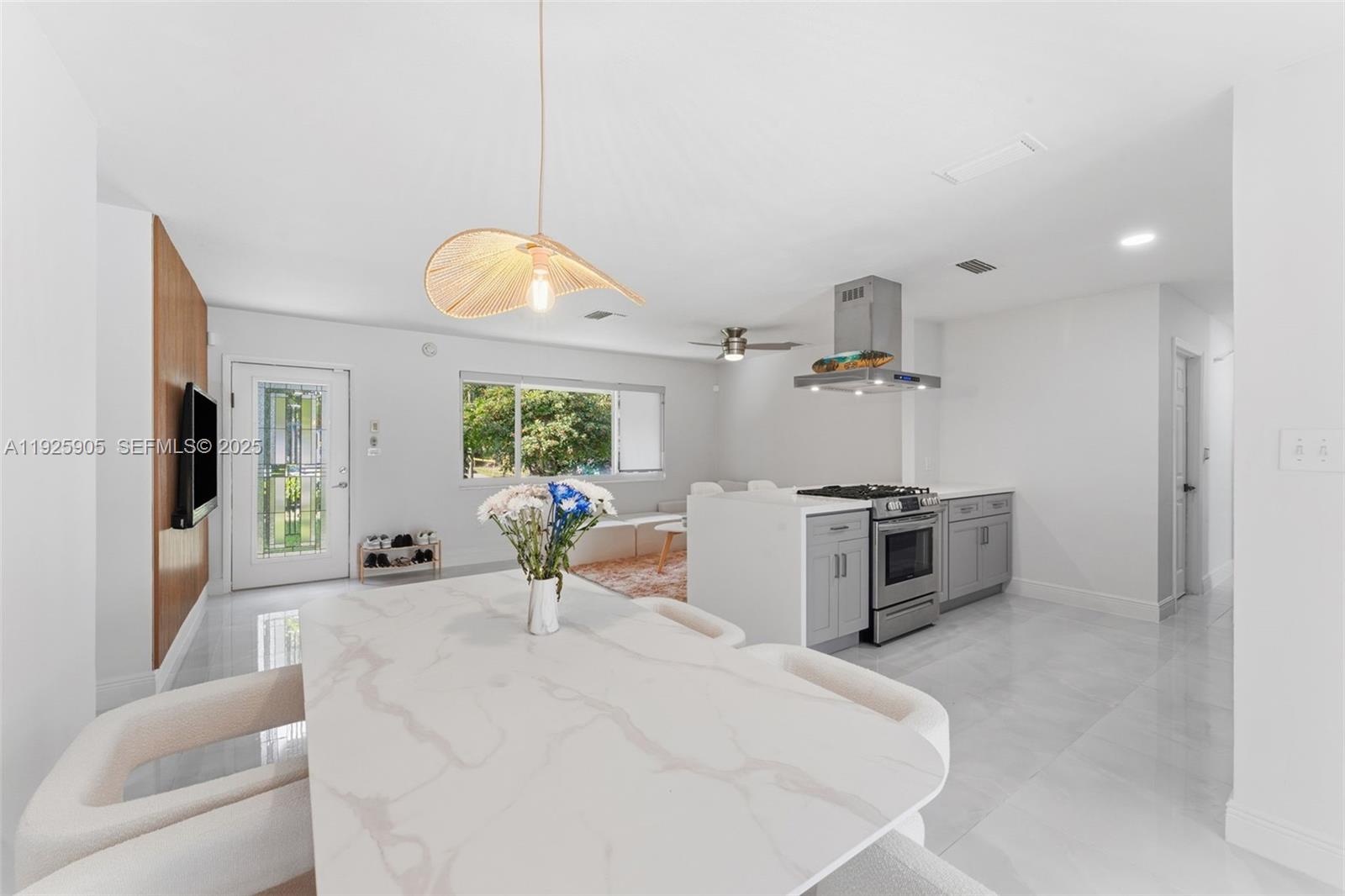 A bright, open-concept kitchen and dining area features white marble surfaces and gray cabinetry — 251 N 71st Ave # 251, Hollywood FL 33024, HOLLYWOOD, FL