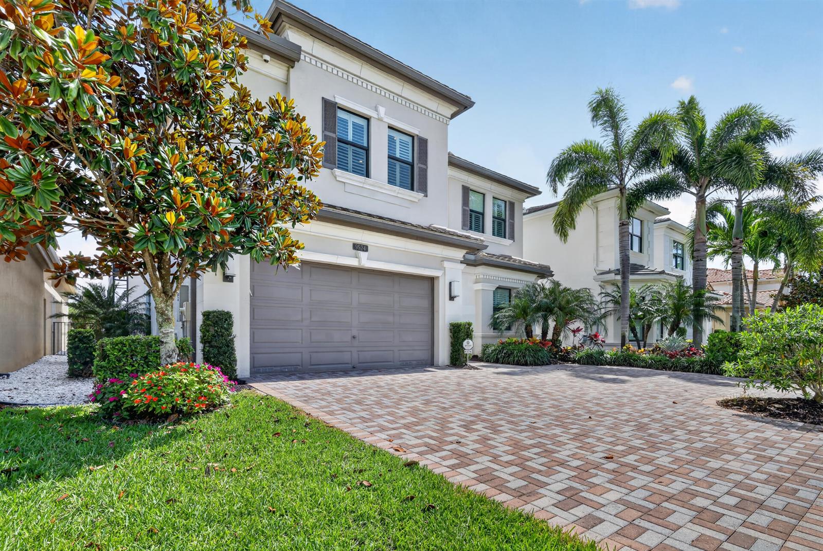 A two-story house with a gray garage door and a paved driveway under a blue sky — 9524 Eden Roc Court, Delray Beach FL 33446, DELRAY BEACH, FL