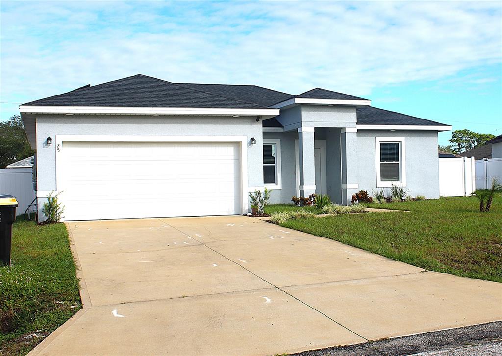 A single-story house with a white garage door, light blue stucco exterior, and dark roof — 25 ZINNIA LANE E, KISSIMMEE, FL