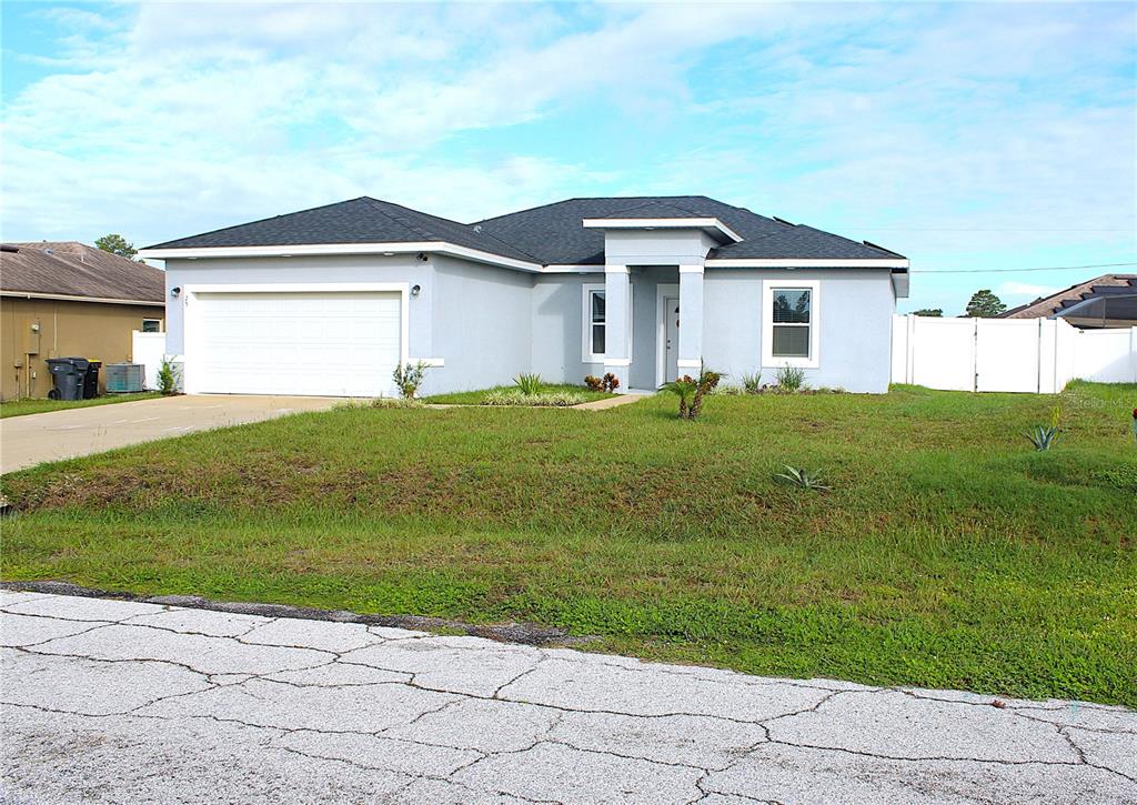 A light blue, single-story suburban house with a two-car garage and a front entrance portico — 25 ZINNIA LANE E, KISSIMMEE, FL