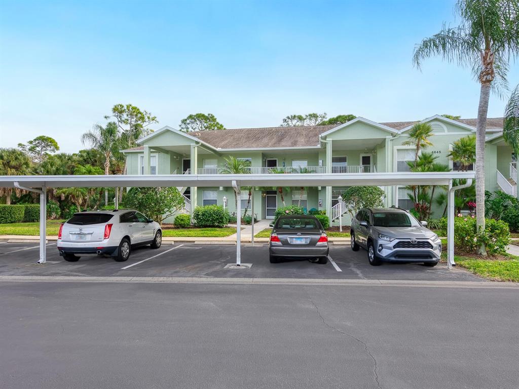 A two-story apartment building features a covered parking area with three parked cars — 4645 TOWER HILL LANE UNIT 2522, SARASOTA, FL