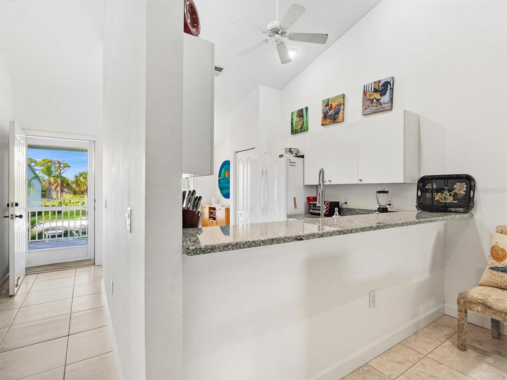 A kitchen with granite countertops, white cabinets, and a view of an outdoor patio area — 4645 TOWER HILL LANE UNIT 2522, SARASOTA, FL