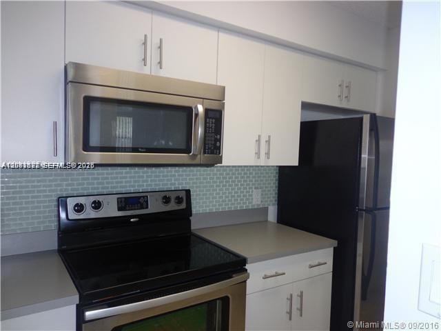 A kitchen features white cabinets, stainless steel appliances, a black refrigerator, and a tiled backsplash — 540 S Park Road # 9, Hollywood FL 33021, HOLLYWOOD, FL