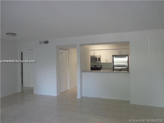 A view of a living area looking toward a kitchen with white cabinets and appliances — 540 S Park Road # 9, Hollywood FL 33021, HOLLYWOOD, FL
