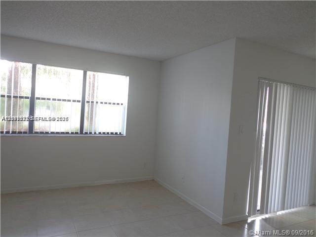 An empty room features white walls, tile flooring, a large window, and vertical sliding blinds — 540 S Park Road # 9, Hollywood FL 33021, HOLLYWOOD, FL