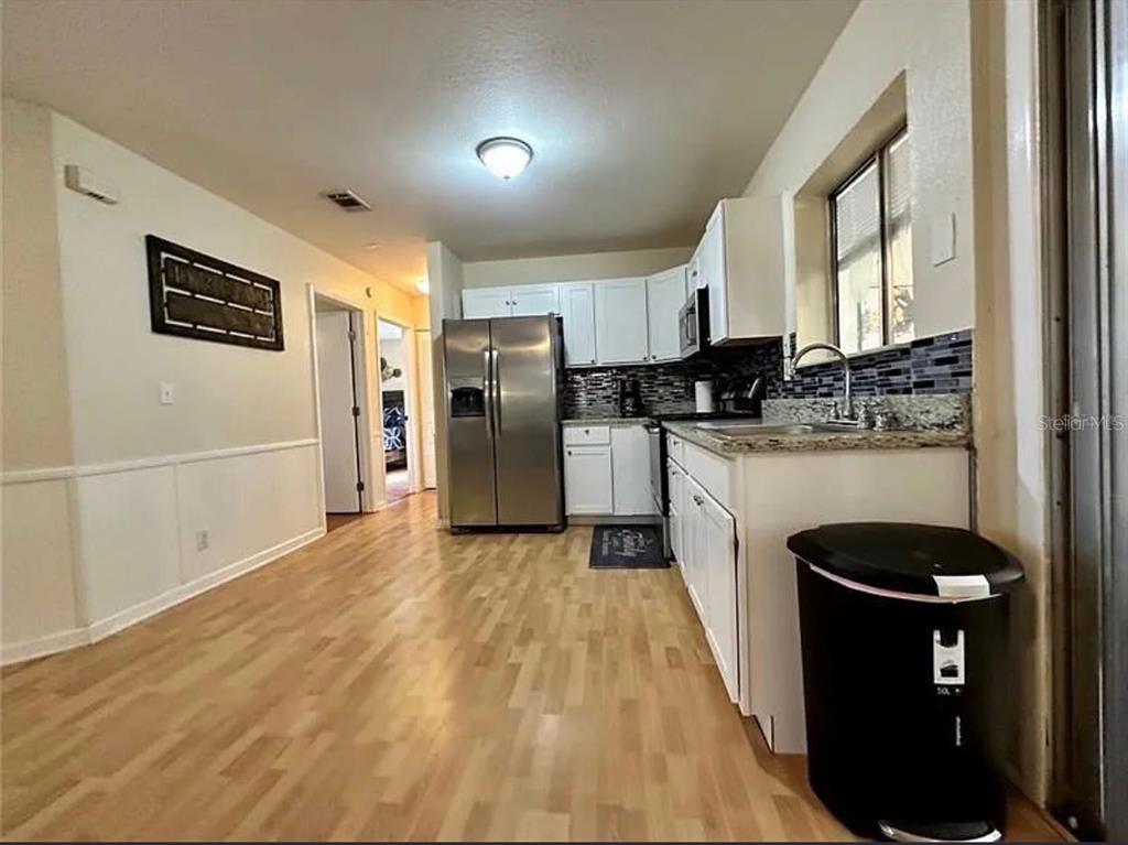 A kitchen with white cabinets, stainless steel appliances, and light wood flooring — 7523 MAYLAND STREET, NORTH PORT, FL