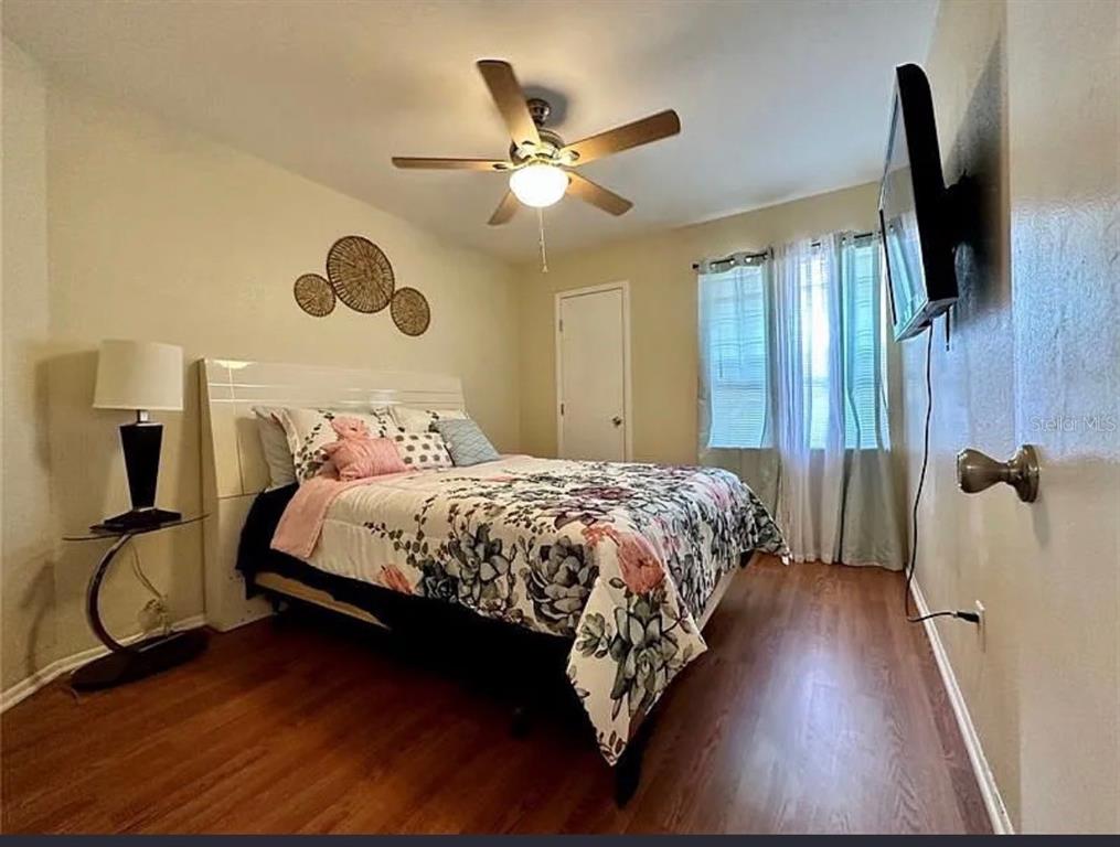 A bedroom features a bed with floral bedding, a ceiling fan, and wood-look flooring — 7523 MAYLAND STREET, NORTH PORT, FL