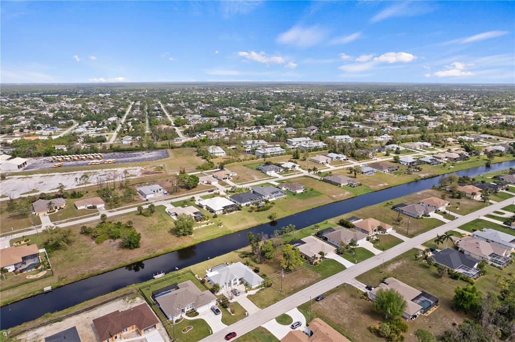 An aerial view shows a residential neighborhood with houses along a canal and a parking lot — 475 ROTONDA CIRCLE, ROTONDA WEST, FL