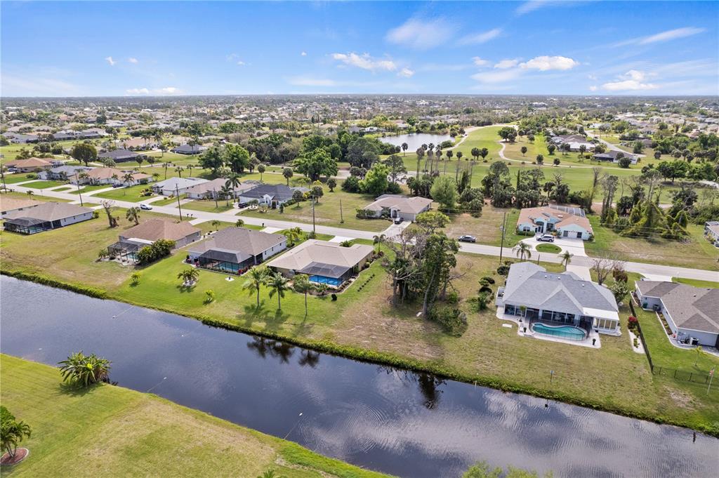 An aerial view shows suburban houses with swimming pools situated along a canal and golf course — 475 ROTONDA CIRCLE, ROTONDA WEST, FL