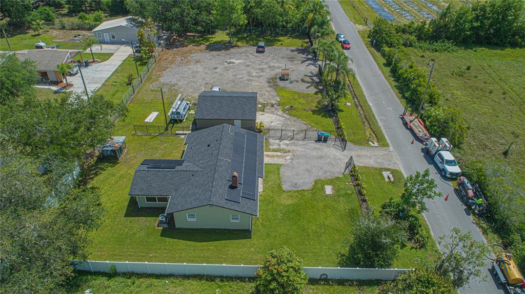 An aerial view shows a house with solar panels, a detached garage, and a gravel lot — 6105 NEW HOPE ROAD, ORLANDO, FL