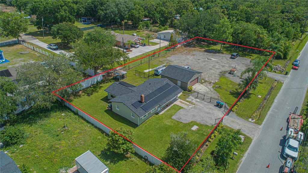 An aerial view shows a house with solar panels and a detached garage on a lot — 6105 NEW HOPE ROAD, ORLANDO, FL