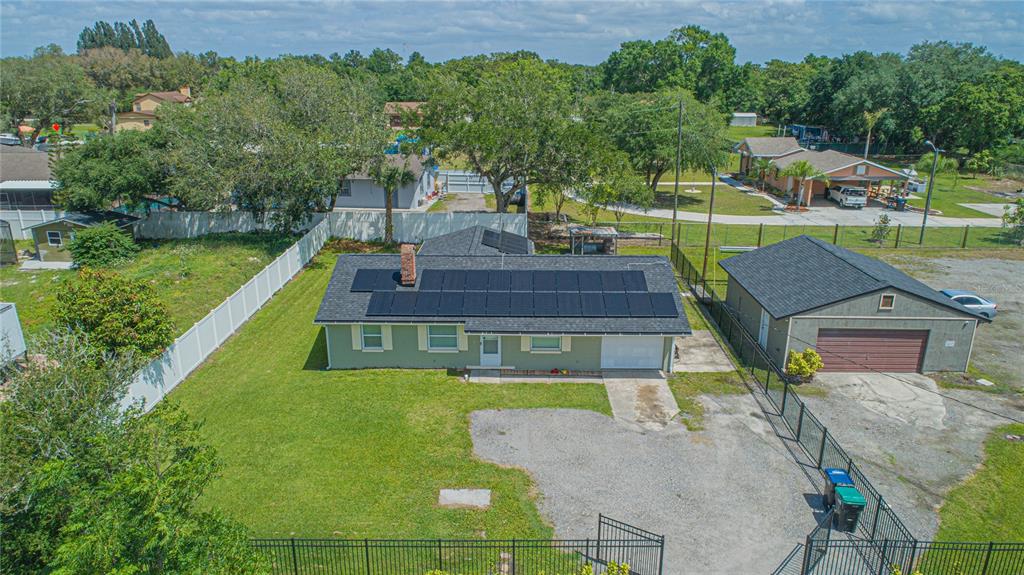 An aerial view shows a single-story house with solar panels and a detached garage — 6105 NEW HOPE ROAD, ORLANDO, FL