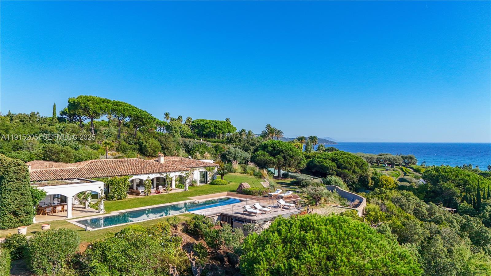 An aerial view shows a Mediterranean-style villa with a long swimming pool overlooking the sea — Allee Des Palmiers La belle, ID 83330, ID