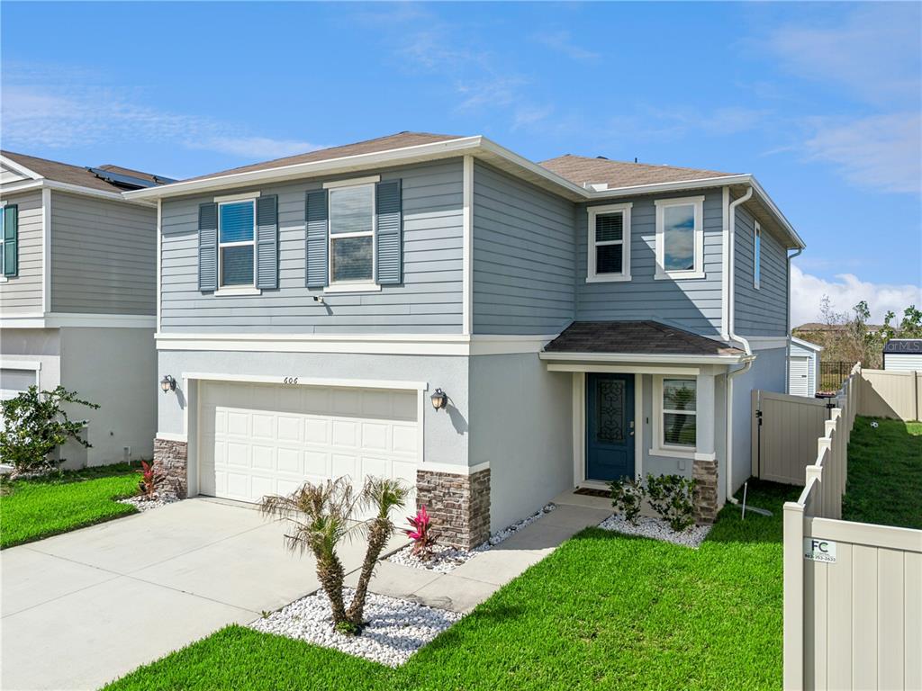 A two-story house with light blue siding, a two-car garage, and a front entrance — 606 PRESERVE POINTE BOULEVARD, DAVENPORT, FL