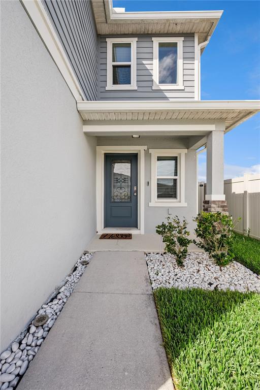 A concrete walkway leads to the front entrance of a two-story house with gray siding — 606 PRESERVE POINTE BOULEVARD, DAVENPORT, FL