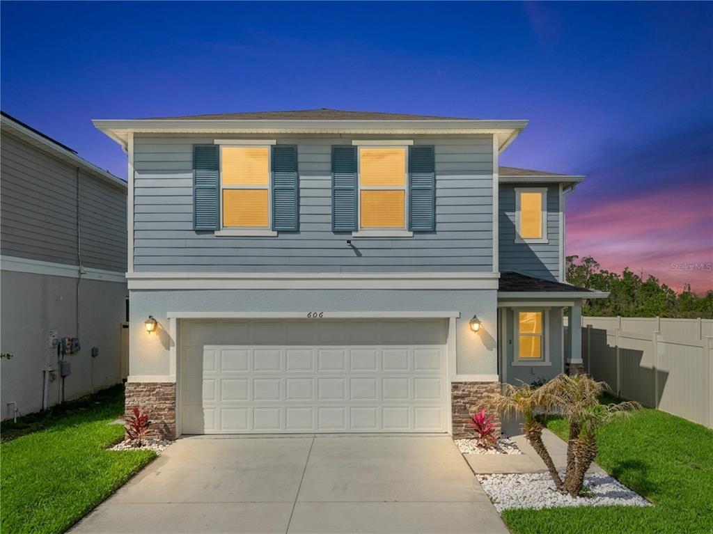 A two-story house with blue horizontal siding, a two-car garage, and stone accents — 606 PRESERVE POINTE BOULEVARD, DAVENPORT, FL