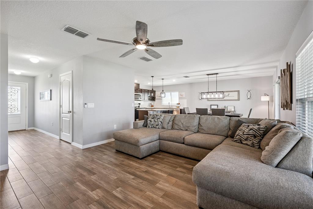 A living room with wood-look tile flooring features a large gray sectional sofa — 606 PRESERVE POINTE BOULEVARD, DAVENPORT, FL