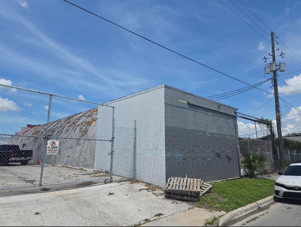 An exterior view of a concrete building with a curved roof behind a chain-link fence — 1001 W PINE STREET, ORLANDO, FL