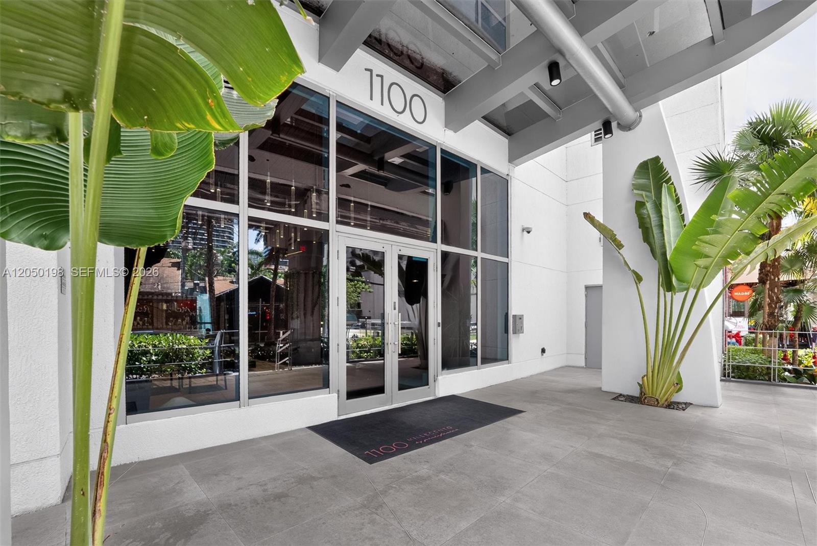 The exterior entrance features glass doors, a large number 1100, and potted tropical plants — 1100 S Miami Ave # 3707, Miami FL 33130, MIAMI, FL