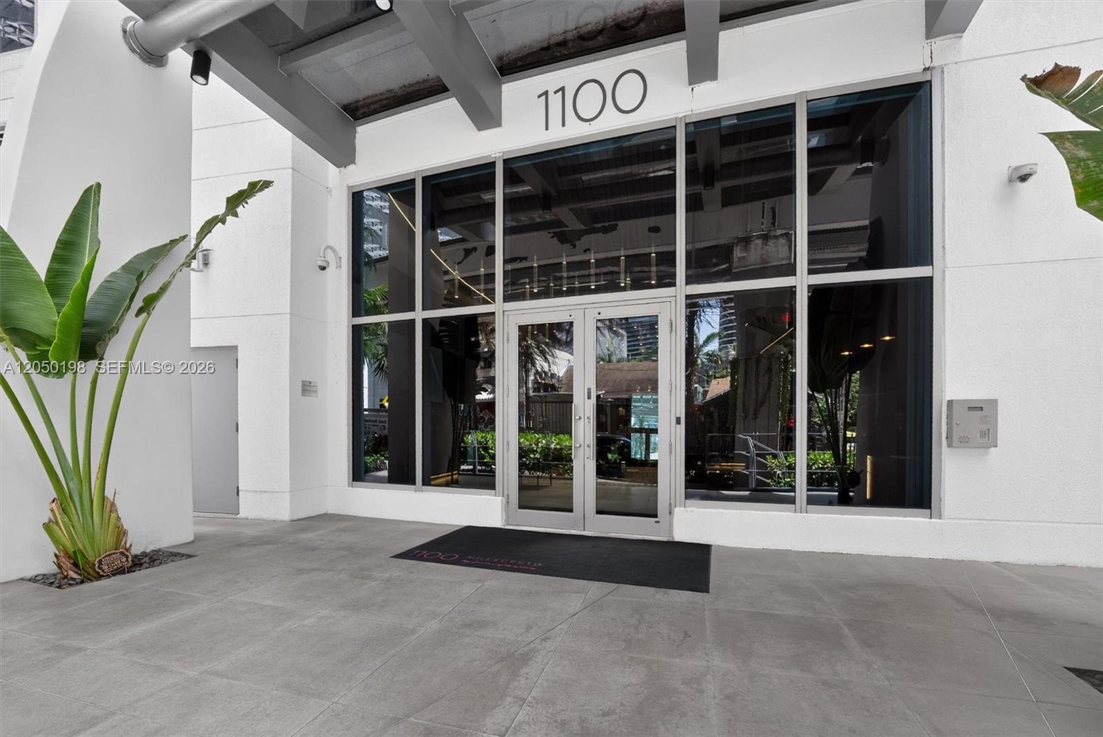 The exterior entrance of a building features glass double doors, large windows, and a plant — 1100 S Miami Ave # 3707, Miami FL 33130, MIAMI, FL