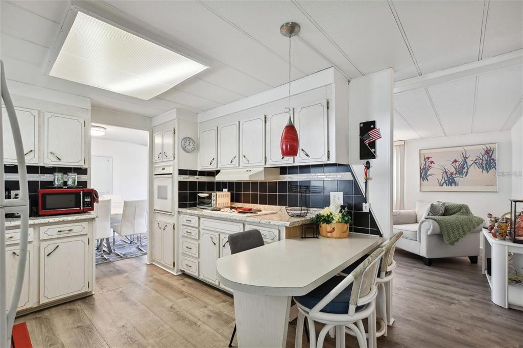 A kitchen with white cabinets, black tile backsplash, and a breakfast bar peninsula — 13225 101ST STREET UNIT 116, LARGO, FL