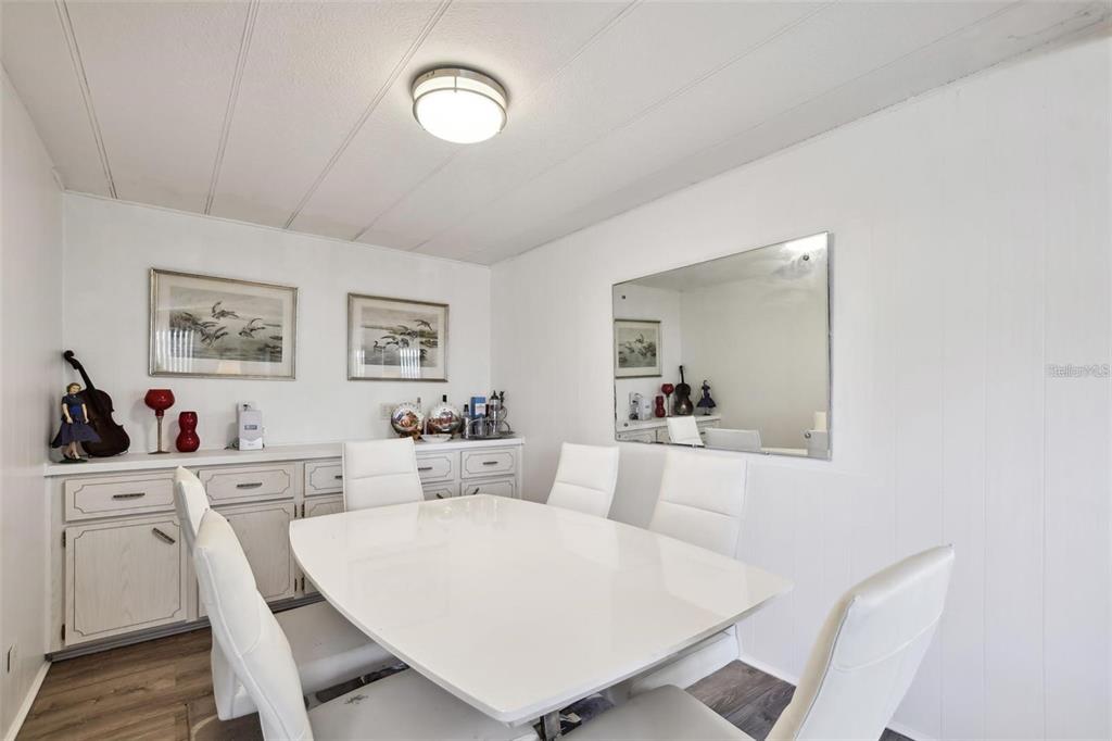 A dining room features a white table, four white chairs, a sideboard, and a mirror — 13225 101ST STREET UNIT 116, LARGO, FL